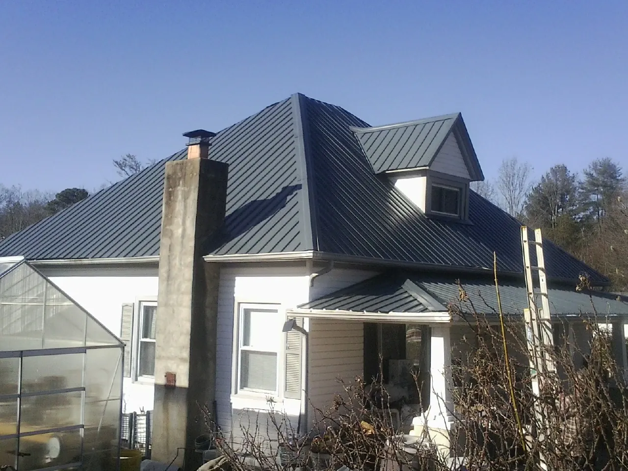 Dark blue standing seam metal roof on a white farmhouse with dormer — Slate & Tile Roof Repair by Roofing Brothers in Pine Bush