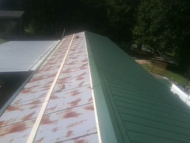 Old rusted panels beside newly installed green metal roofing — Wind Damage Roof Repair by Roofing Brothers in Pine Bush