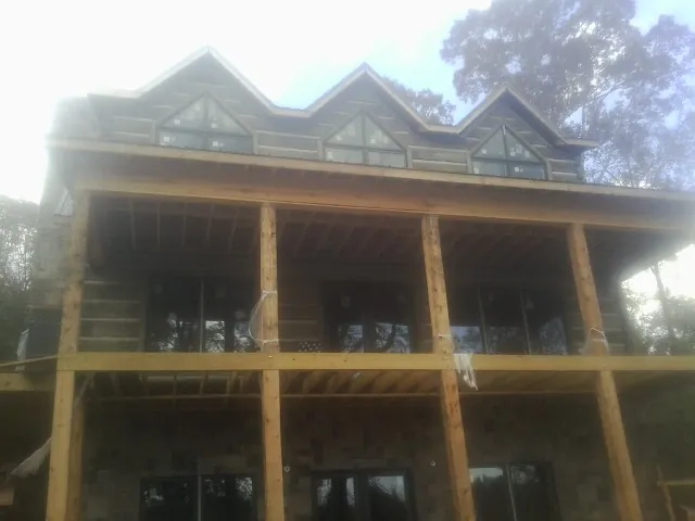 Dormers and porch framing on a large log home under construction — Roof Coating work by our crew in Pine Bush