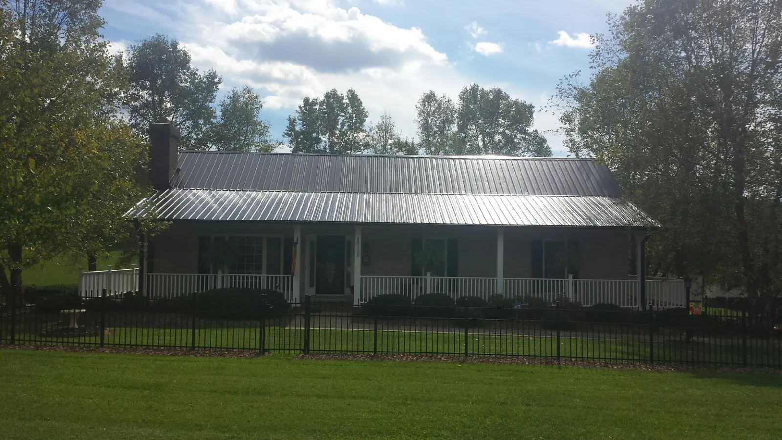 Gray metal roof on a brick ranch with a full width front porch — Gutter Guard Installation work by our crew in Pine Bush