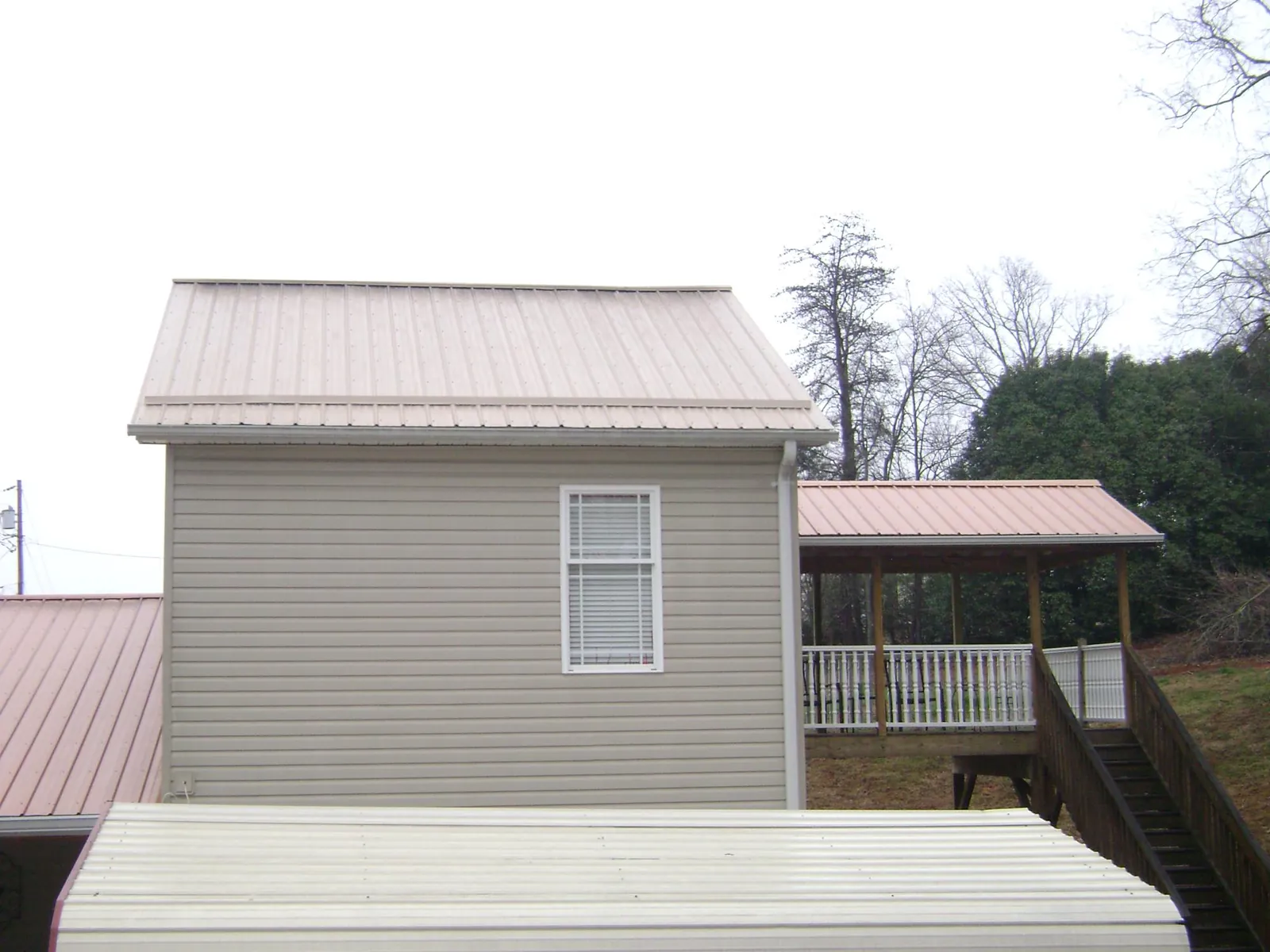 Tan metal roofs on a two story addition and attached porch, from a Roof Replacement job in Pine Bush