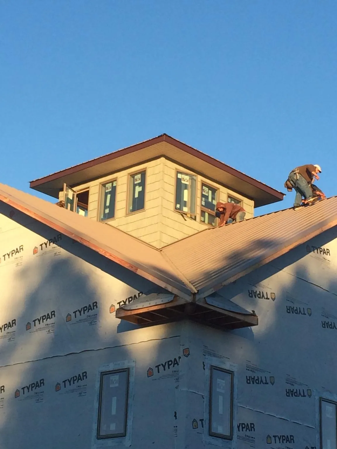 Roofers working around a rooftop cupola on a new metal roof at sunset — Roof Waterproofing in Pine Bush by Roofing Brothers
